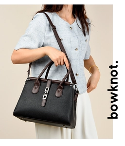 Detail of black pebbled leather tote bag with brown straps and silver turn-lock buckle