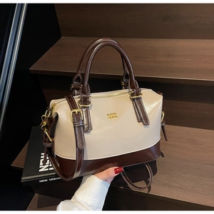 Detail of bicolored soft leather boston bag with golden hardware and adjustable strap