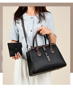 Close-up of black lychee grain tote bag with brown handles and matching envelope wallet