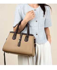 Detail of khaki and brown leather tote bag showing silver metal buckle and rivets