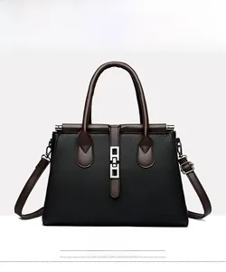 Front view of black trapezoid tote bag with brown contrast straps and metal buckle