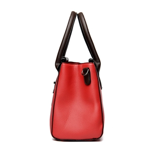Red pebbled leather tote bag with trapezoid structure and dark handles in side view