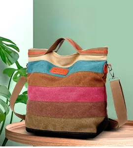 Detail view of a striped canvas tote bag with brown leather logo and adjustable shoulder strap
