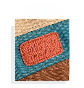 Detail of colorful stitched canvas bag with orange leather logo patch and clear texture