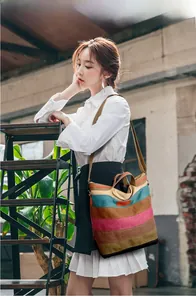 Model showcasing a multi-color striped canvas tote bag with adjustable brown shoulder strap