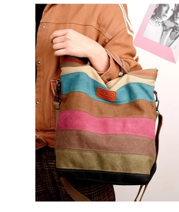 Detail of color-block canvas tote bag with striped pattern and leather logo patch