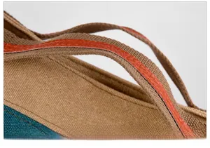 Detail of canvas tote featuring navy blue stitching and orange leather handle trim