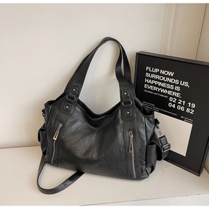 Detail of black leather dumpling bag featuring metal rivets and decorative zippers