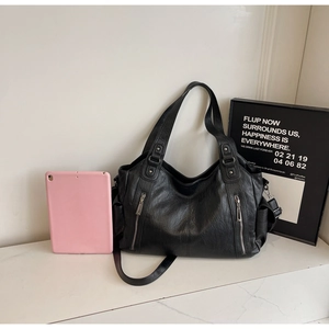 Detail view of black PU leather tote bag with functional vertical zipper pockets and dual straps