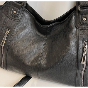 Close-up of black PU leather tote showing grain texture and silver zipper details