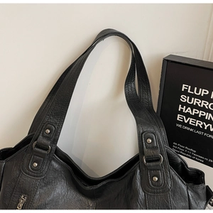 Detail of black pebbled leather dumpling bag with silver rivets and zipper features