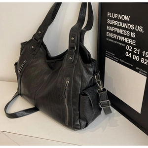 Detailed macro view of black faux leather dumpling bag with multiple zipper pockets
