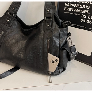 Detail of black matte PU leather tote bag showing side pocket with a phone for capacity