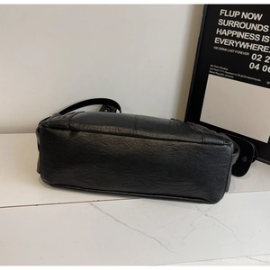 Detail view of the stitching and base of a black PU leather tote bag on a white background