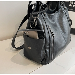 Close-up of black leather tote bag showing side magnetic pocket and smooth texture