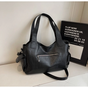 Detail of black pebbled leather tote bag with silver zippers and adjustable strap