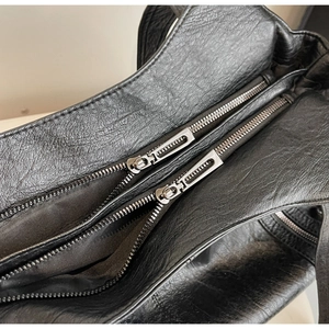 Close-up of dual silver zippers and textured black leather on large tote bag