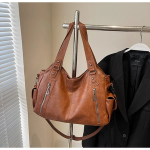 Macro detail of dark brown retro leather tote featuring functional zippers and side pocket