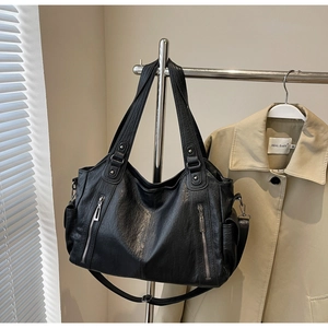 Detail of black faux leather tote with metal zippers and adjustable shoulder strap