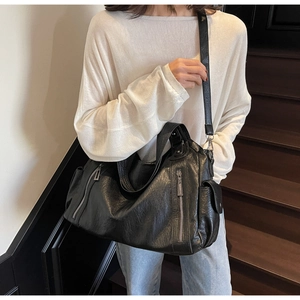 Detail of black faux leather tote with metal zippers and cargo pockets in street style