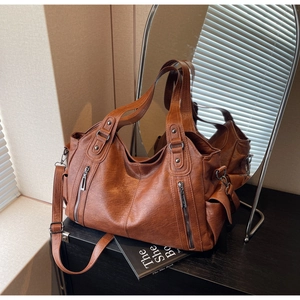 Macro view of vintage brown leather tote bag with vertical zippers and adjustable strap