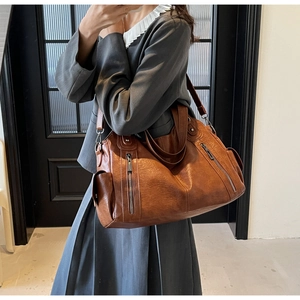 Mirror selfie showing a brown retro leather tote bag worn by a model in a modern room