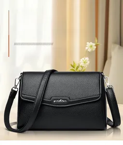 Close-up of black pebble leather texture and metallic logo on minimalist crossbody bag
