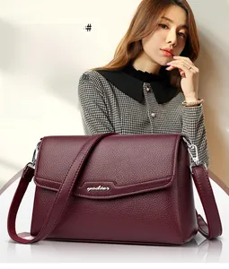 Close-up of wine red litchi grain leather shoulder bag with metallic clasp and strap