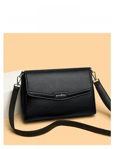 Close-up of black lychee grain leather crossbody bag with metallic silver logo detail