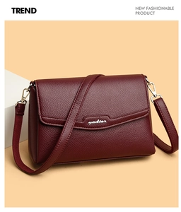 Detail of burgundy lychee grain leather handbag with gold hardware and shoulder strap