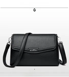 Detail of black lychee grain leather crossbody bag featuring a metal logo and slim strap