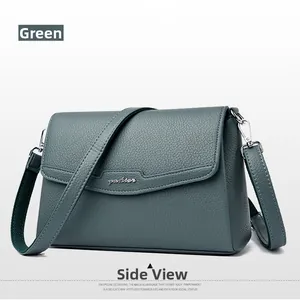 Detail of dark green pebble leather crossbody bag with silver logo and adjustable strap