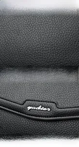 Close-up of black lychee grain leather texture and silver Fadier brand logo on shoulder bag