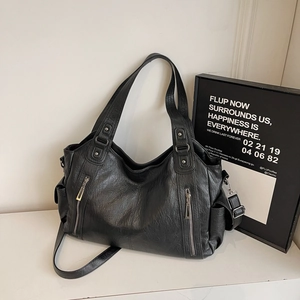 Black leather tote bag with pebble texture and dual front zippers on a white surface