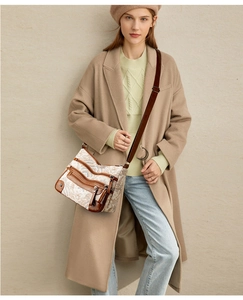 Detail of vintage printed crossbody bag with multi-pocket layout on a beige coat