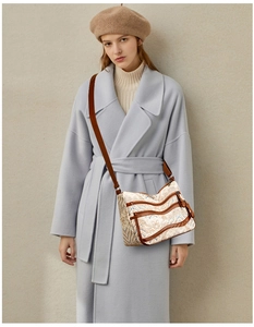 Detailed view of wavy pattern crossbody bag with brown leather strap worn by a model