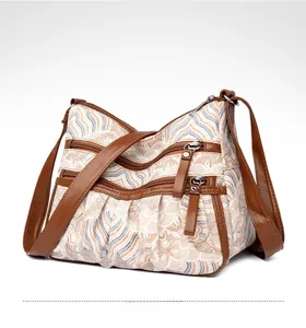 Detail of crossbody bag featuring multi-zipper compartments and blue wave patterns