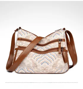 Detail showing wave pattern embroidery and multi-pocket design on the crossbody bag