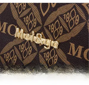 Gros plan du logo doré Mei&ge et du motif M vintage sur le sac fourre-tout en cuir brun