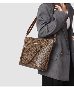 Vue latérale d'un sac cabas classique marron à monogramme porté avec un blazer gris