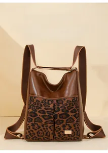 Detail of brown leather backpack with leopard print panel and gold metal logo plaque