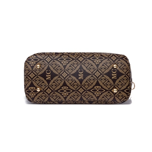 Vue du dessous du cabas marron rétro avec pieds de protection dorés et motif monogramme