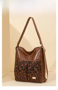 Detail of brown PU leather tote bag featuring leopard print pocket and metal logo plate