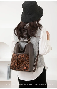 Rear view of a leopard print and brown faux leather backpack worn by a model