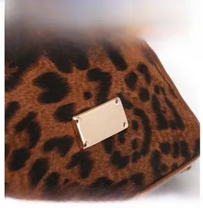 Detail view of leopard print faux fur bag with a polished gold metallic brand plate