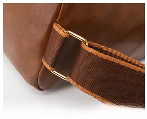 Detail of reinforced strap stitching and gold metal D-ring on brown leather bag