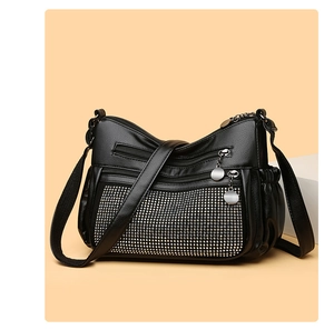 Détail du sac bandoulière en cuir noir avec clous argentés et multiples fermetures éclair