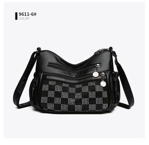 Détail du sac bandoulière noir avec motif damier en strass et compartiments zippés multiples