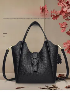 Detail of black lychee grain leather bucket bag with teddy bear charm and strap