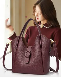 Macro view of burgundy lychee leather texture and bear charm on bucket handbag